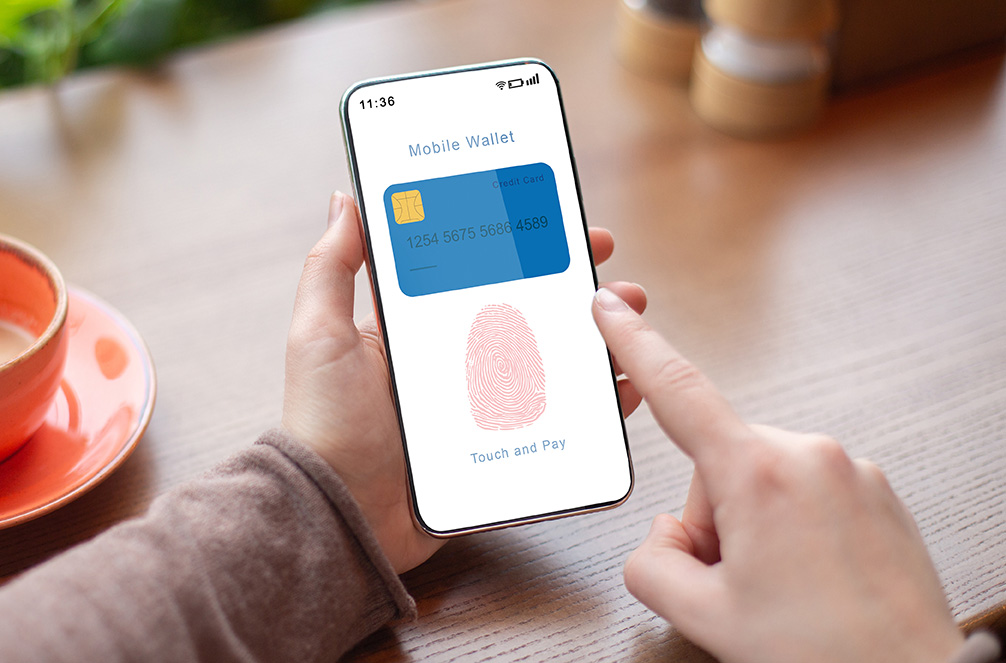 Online Payment And Biometric Identification Concept. Over The Shoulder View Of Person Holding Smartphone In Hand Showing Mobile Wallet App With Fingerprint Icon On Device Screen For Scanning
