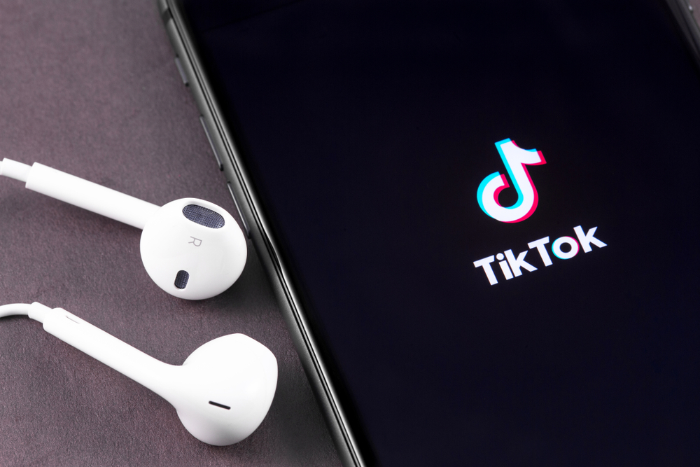 Tiktok,Logo,On,The,Screen,Iphone,With,Earpods,Headphones,Closeup.