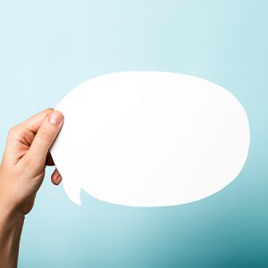 Mano sosteniendo un recorte representando una burbuja de diálogo