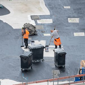 dos personas impermeabilizando el techo de un edificio