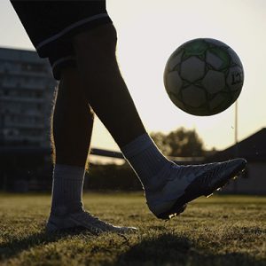 Acercamiento a los pies de una persona jugando con un balón de futbol soccer