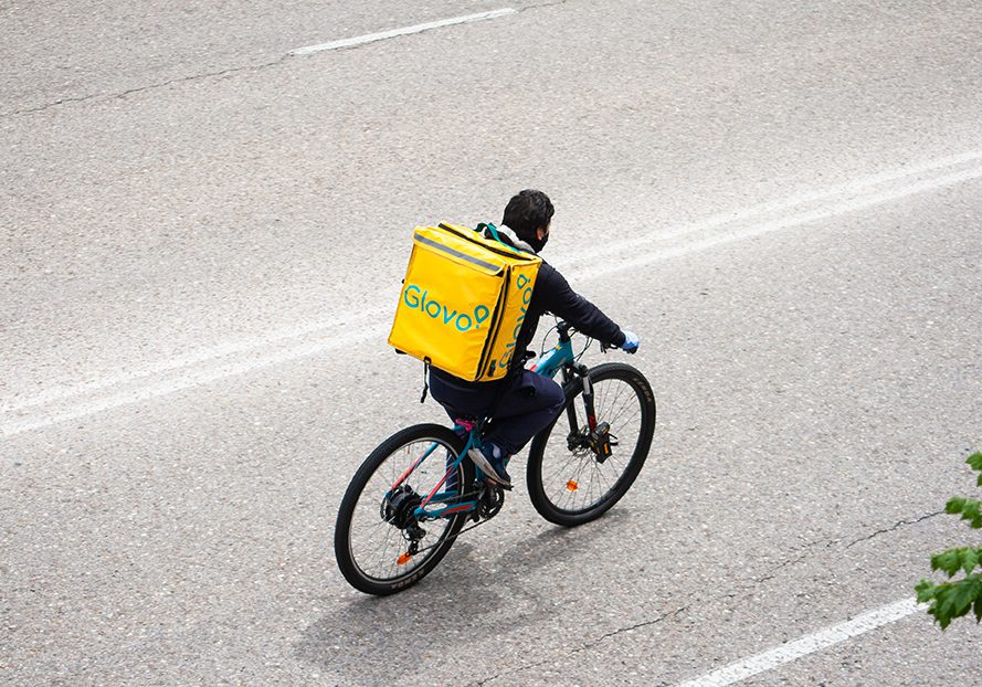 San Sebastian de los Reyes, Madrid, Spain; 04/18/2020: Glovo company worker during the coronavirus alert, distributing merchandise in his backpack riding a bicycle